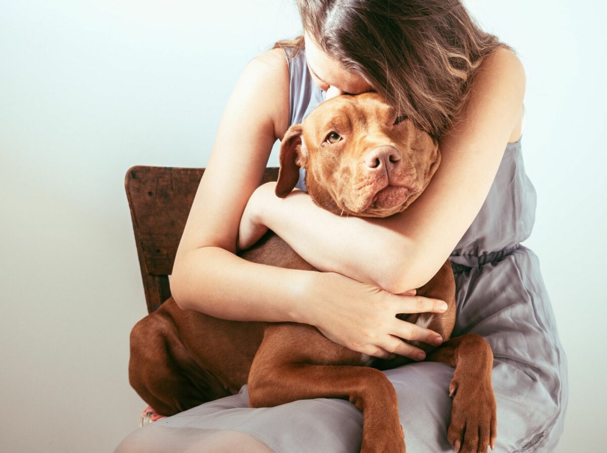 A woman hugging her dog on a chair.