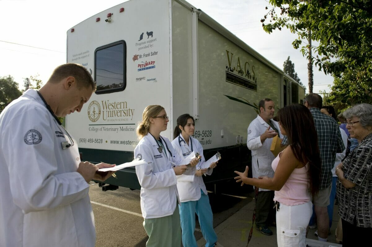 A group of people standing in front of a medical truck.