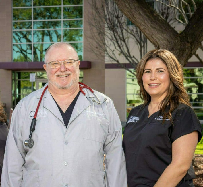 The administration team for the WesternU PHC (Dr. David Clark, Annette Chavarria-Marron, and Jennie Jennings), smiling outdoors near the PHC building, with trees in the background.