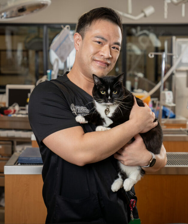 RVT Peter Hoang holding his pet cat in the PHC with medical equipment in the background.