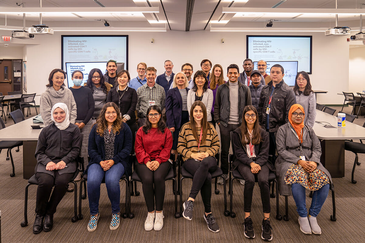 25 students in classroom with monitor displays behind them