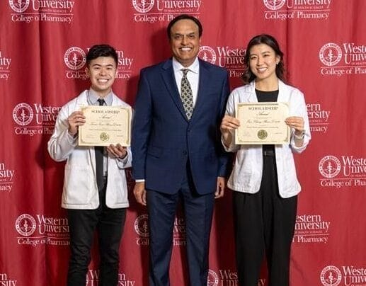 Two students in white coats hold certificates while standing with a man in a suit in front of a Western University College of Pharmacy backdrop.