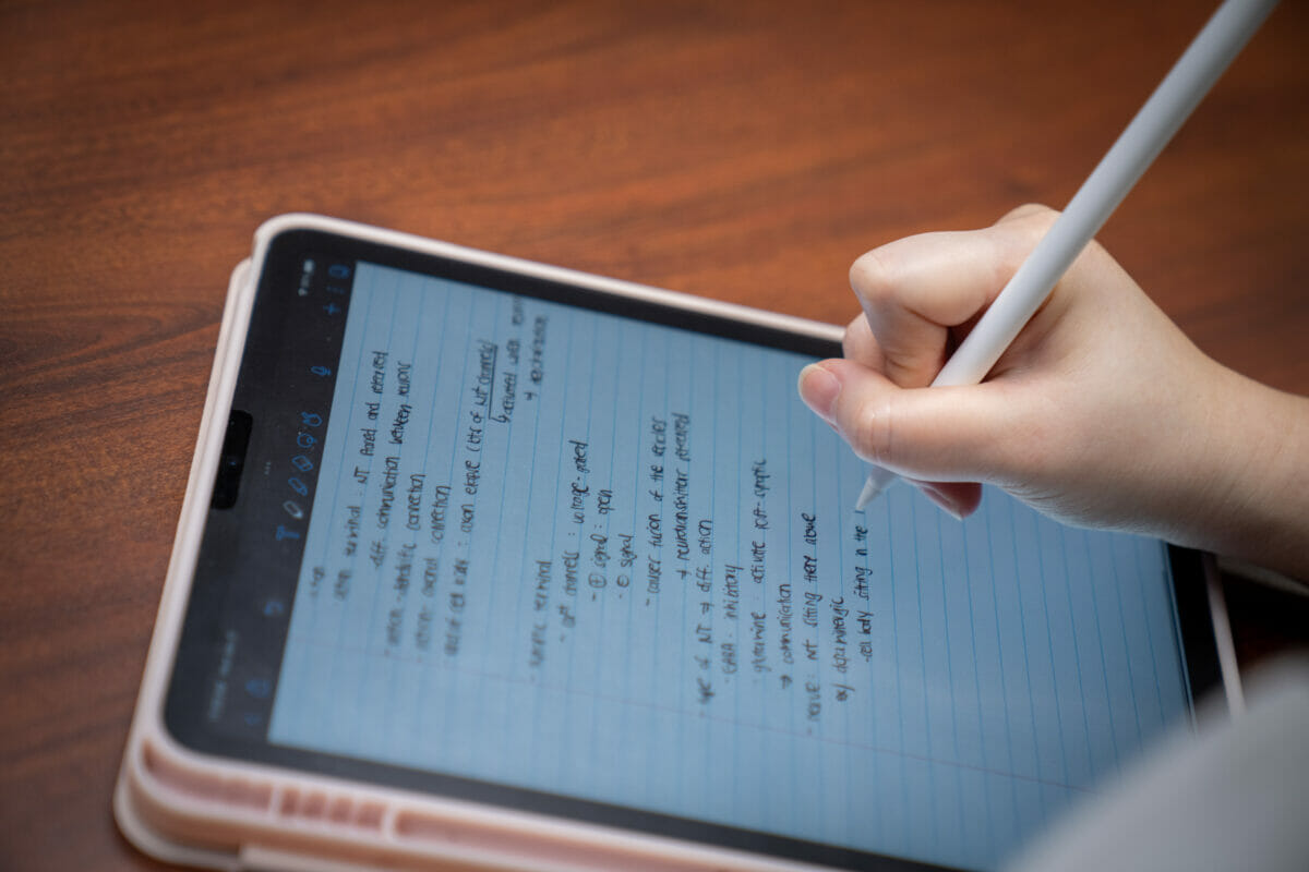 a person writing on a tablet with a pen.