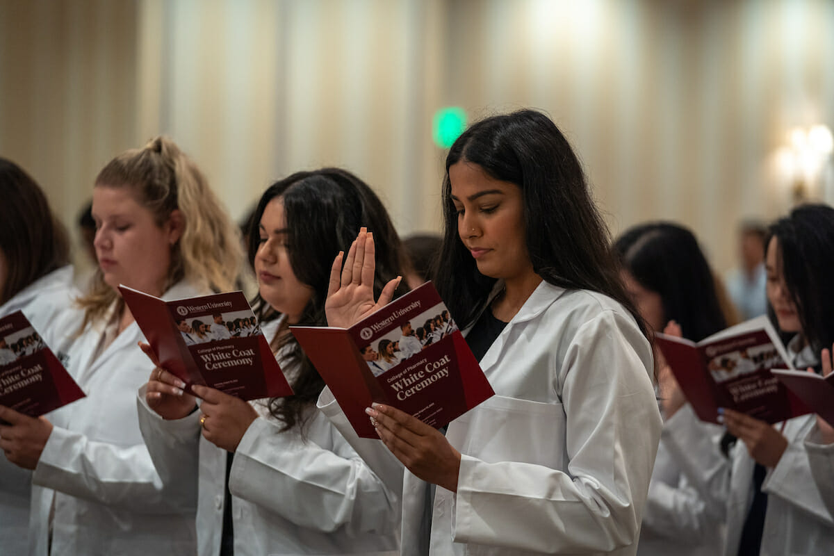 A group of women in lab coats reading books.