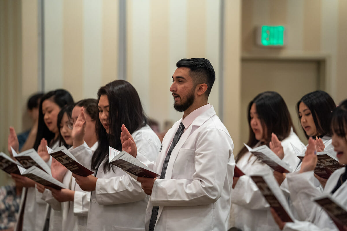 A group of people in white coats singing in a choir.