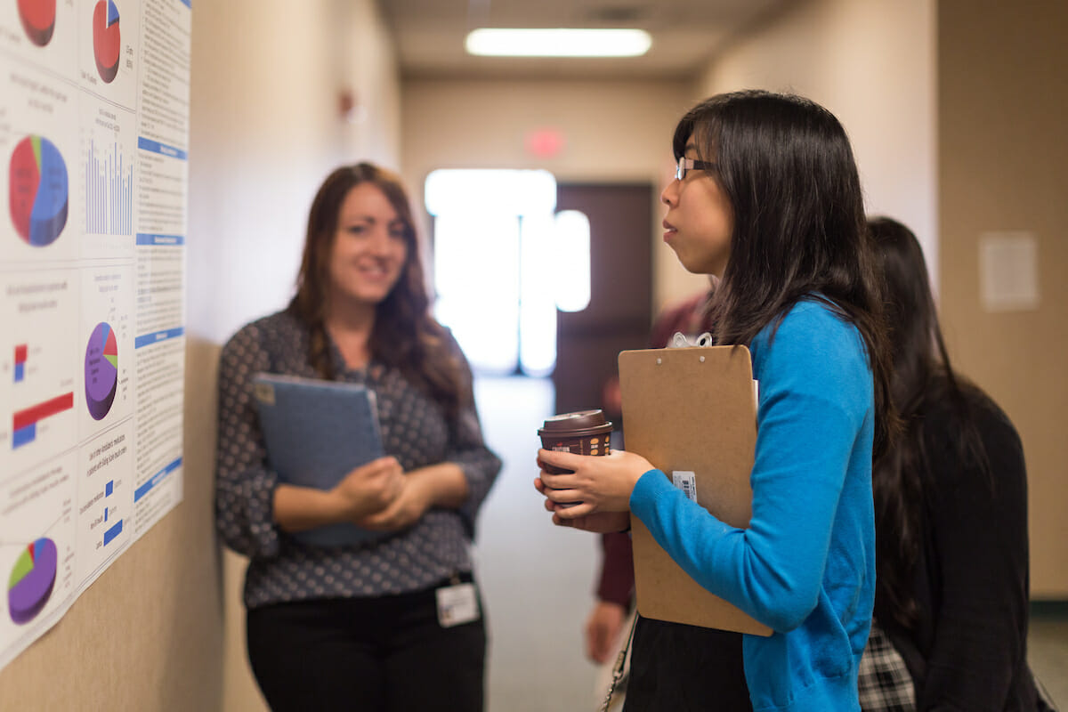 AE Poster Day, woman looks at the poster on the wall