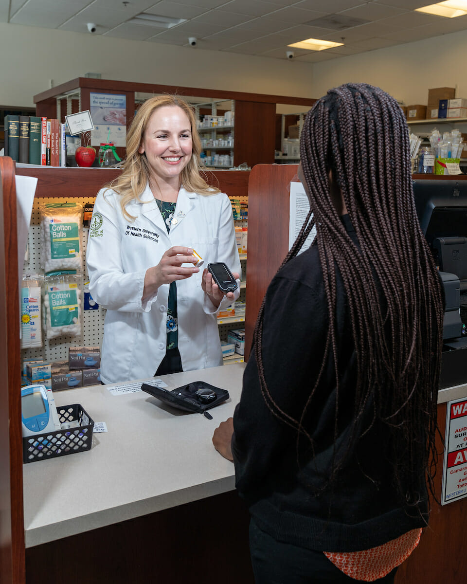 Pharmacys student explaining medication to customer at counter