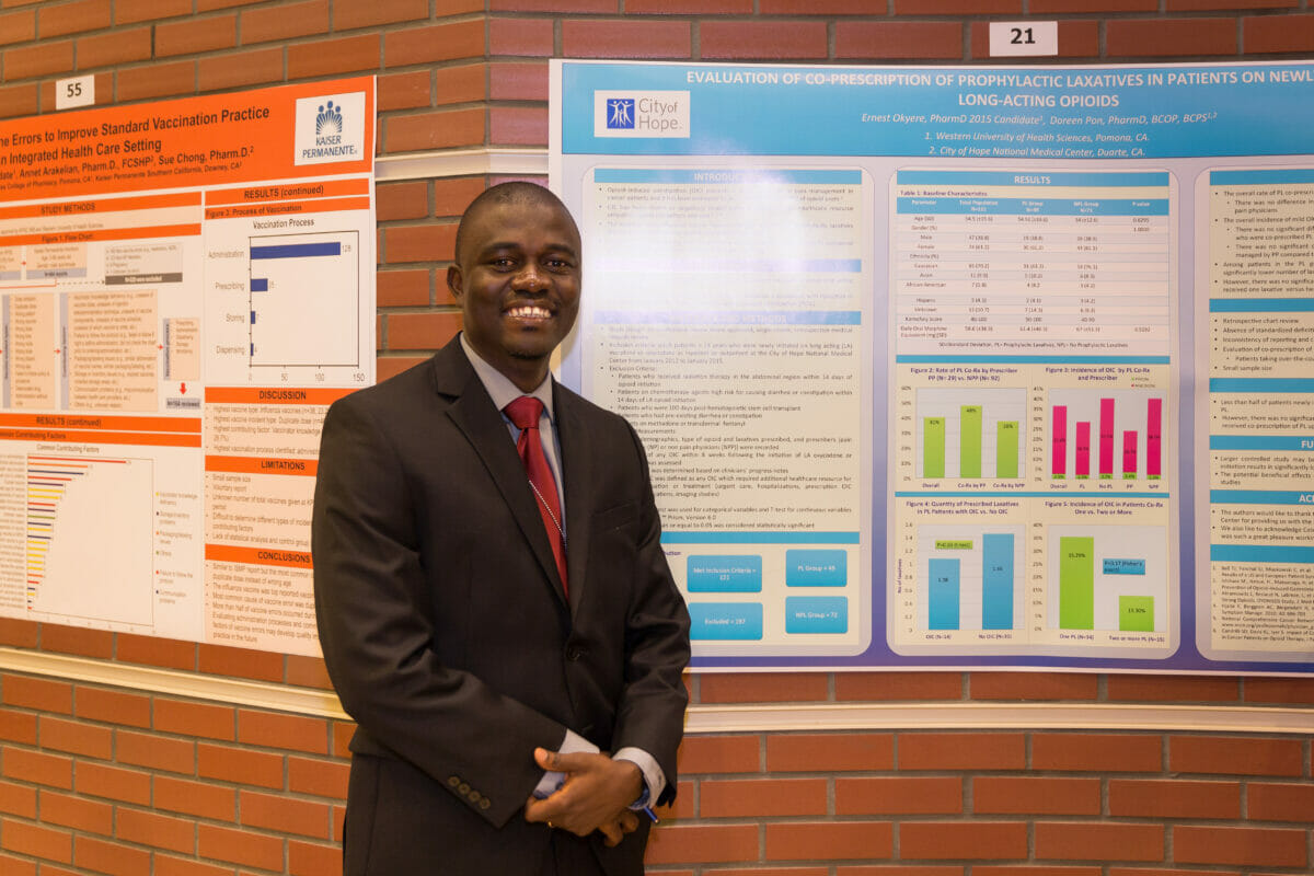 Student in a suit standing in front of research poster