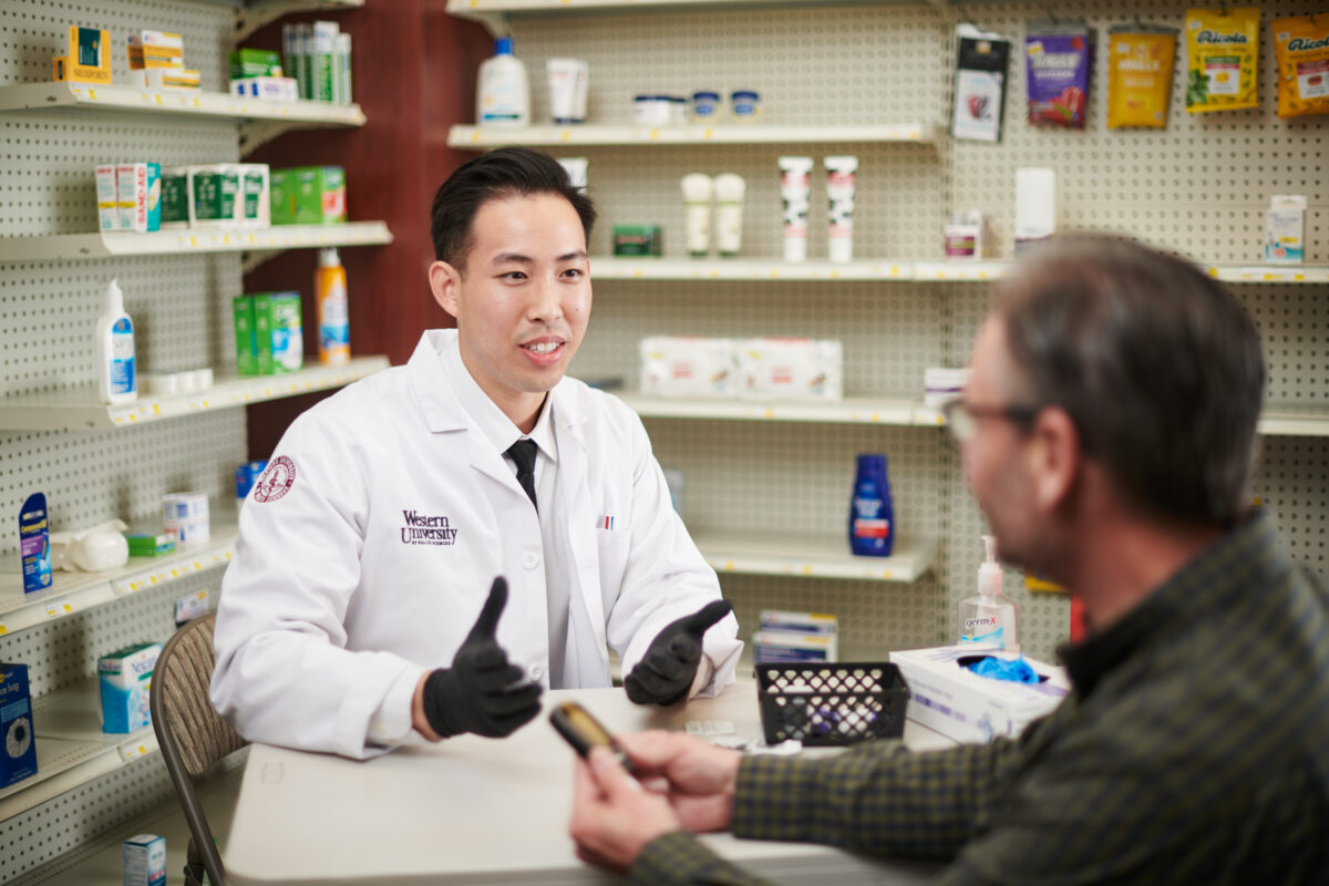 WesternU PCC Pharmacy. Pharmacist talking with a patient.