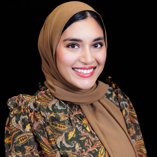 A woman in a hijab smiling for the camera.
