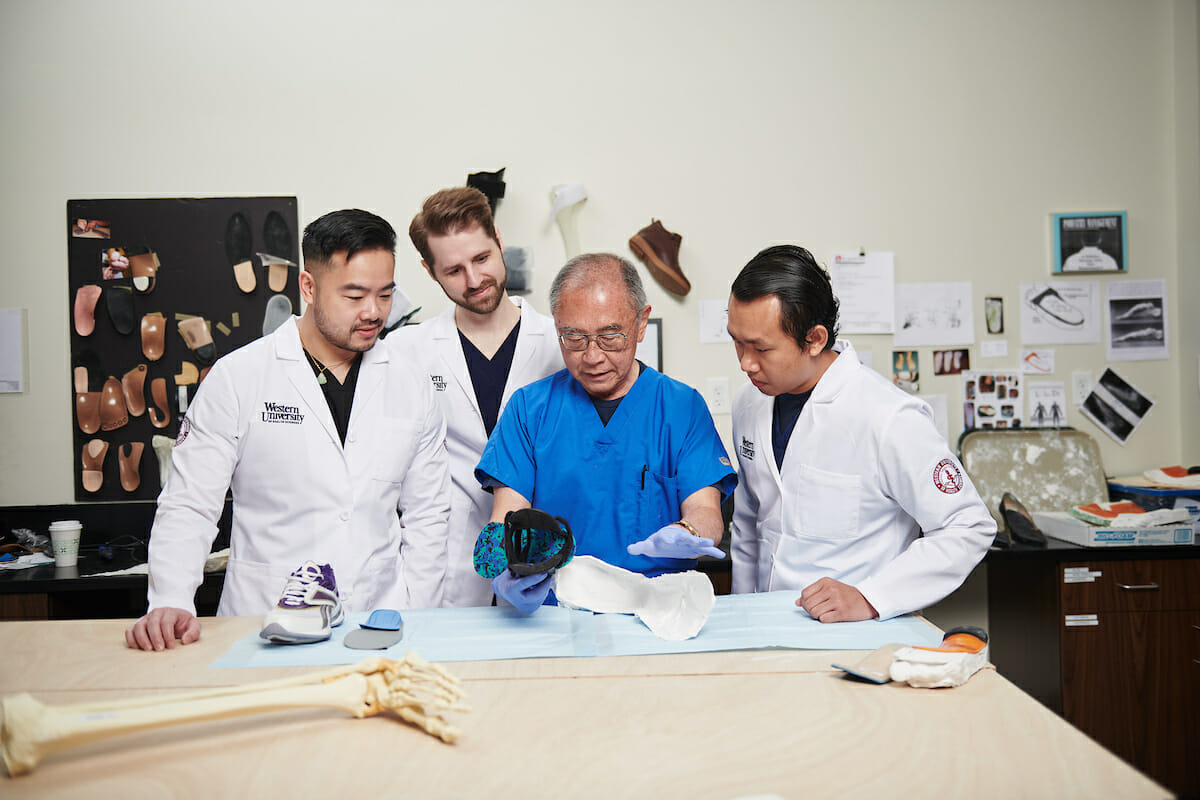 A group of Podiatric Medicine students examining a table.