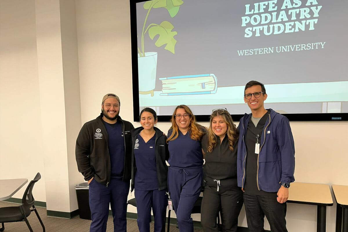 A group of people in scrubs standing in front of a screen.