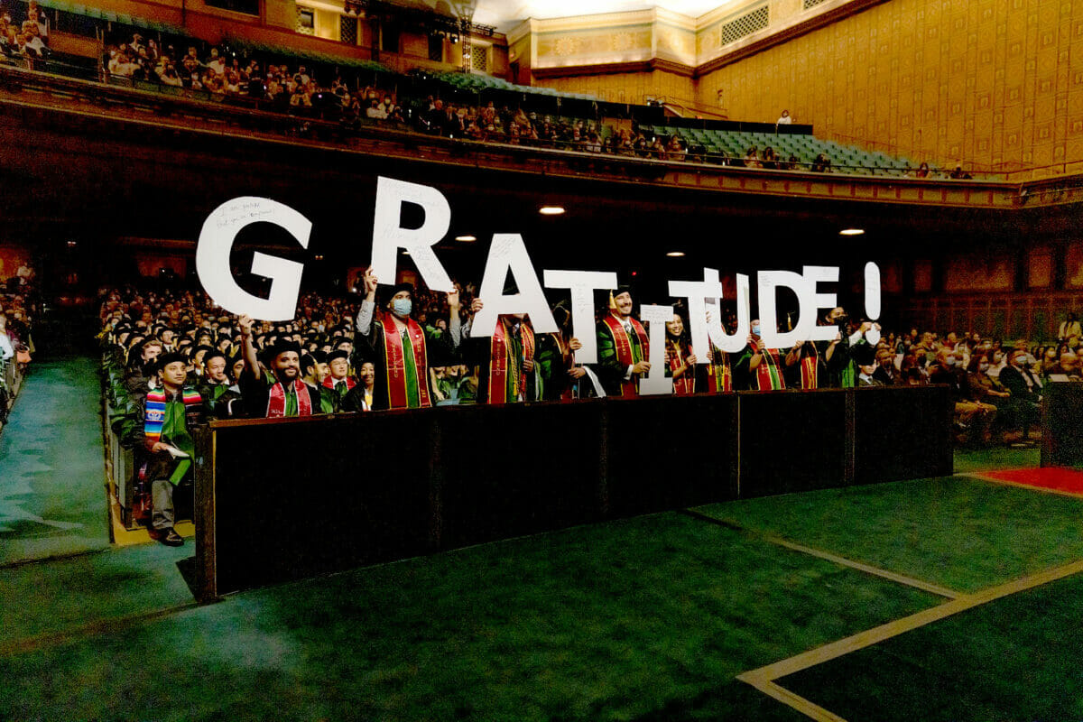 students in auditorium holding signs saying gratitude!