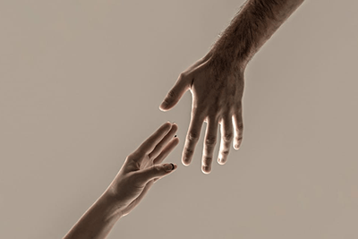 Two outstretched hands reach toward each other against a neutral background.