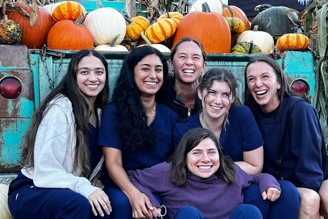 A group of students posing for a photo in front of pumpkins.