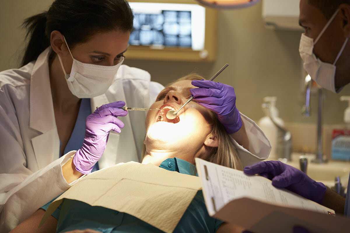 Image of a patient in dentist chair getting an examination from the dentist