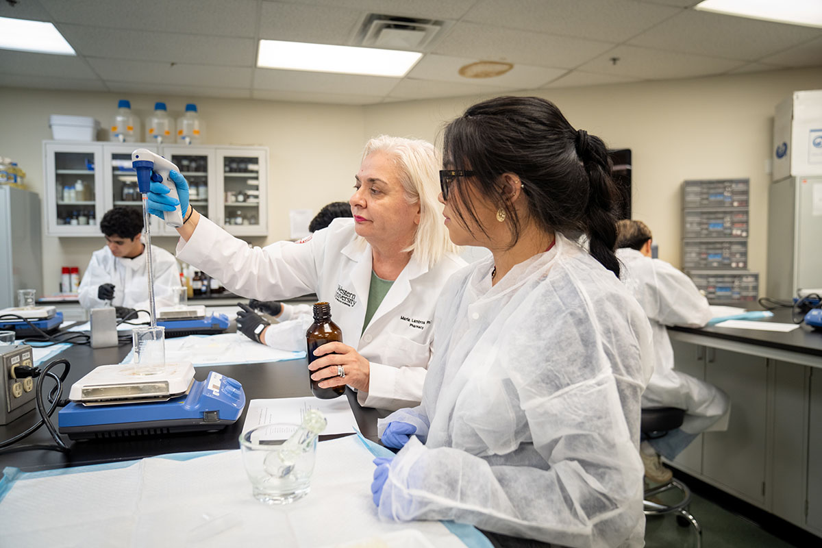 Two women in lab coats working in a lab at WesternU Pharmacy.