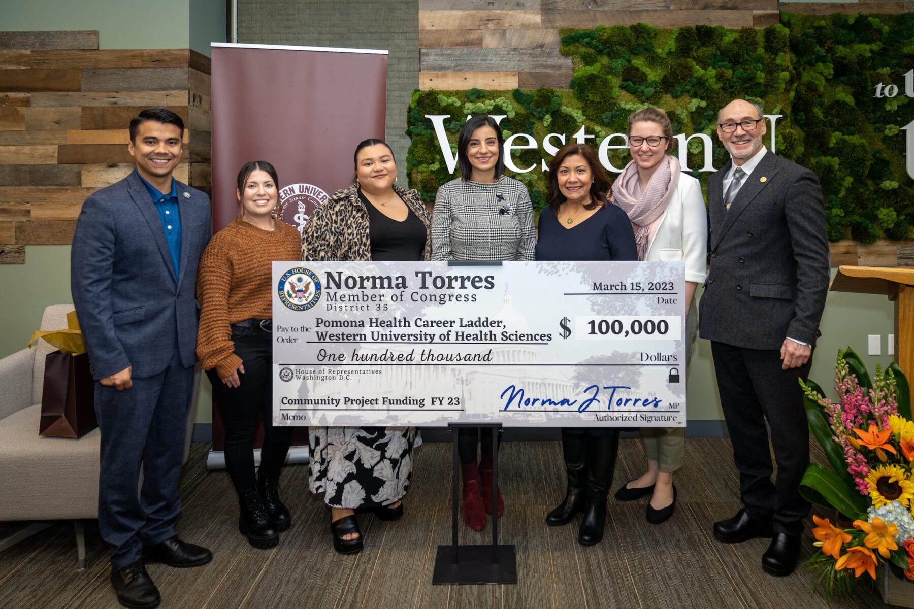 Seven people standing behind a large check, $100,000 donation