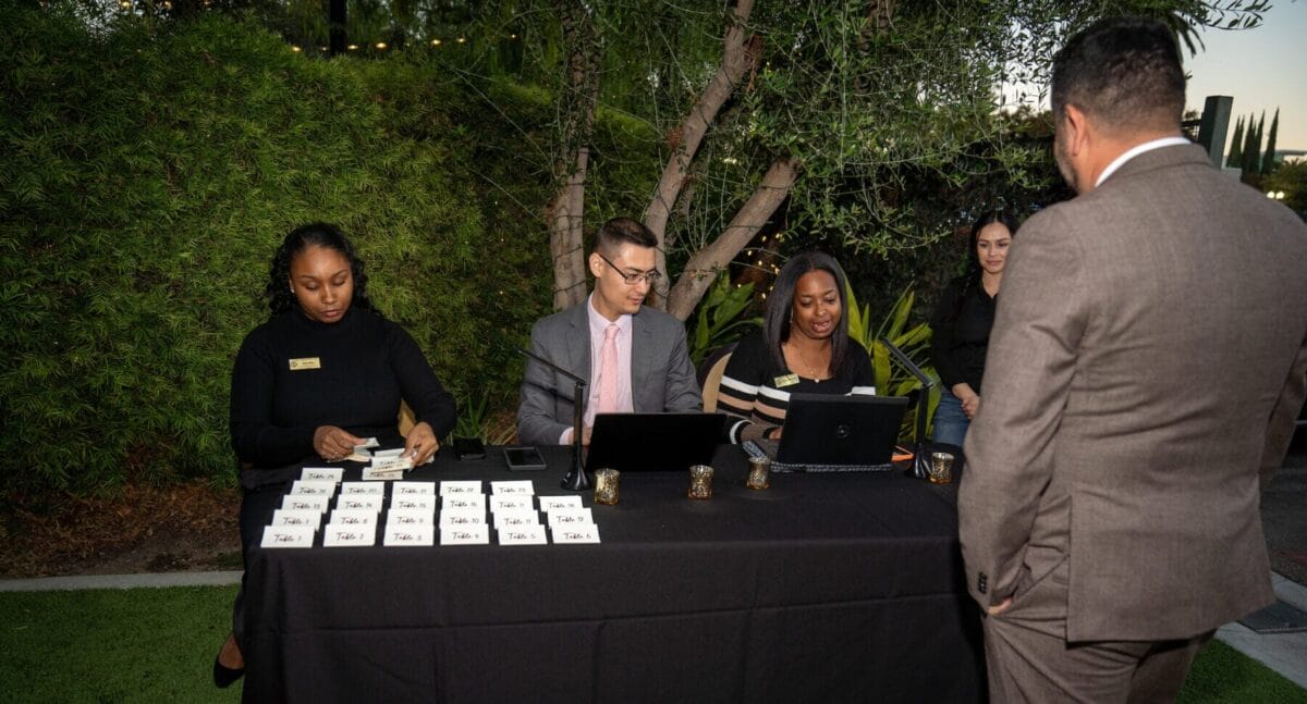Two females, one male, sitting at a table registering people for an event