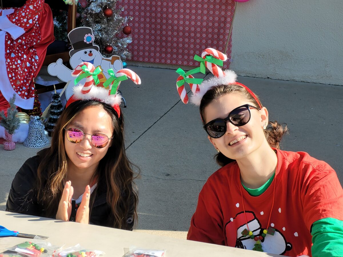 Two students wearing santa hats at a table.