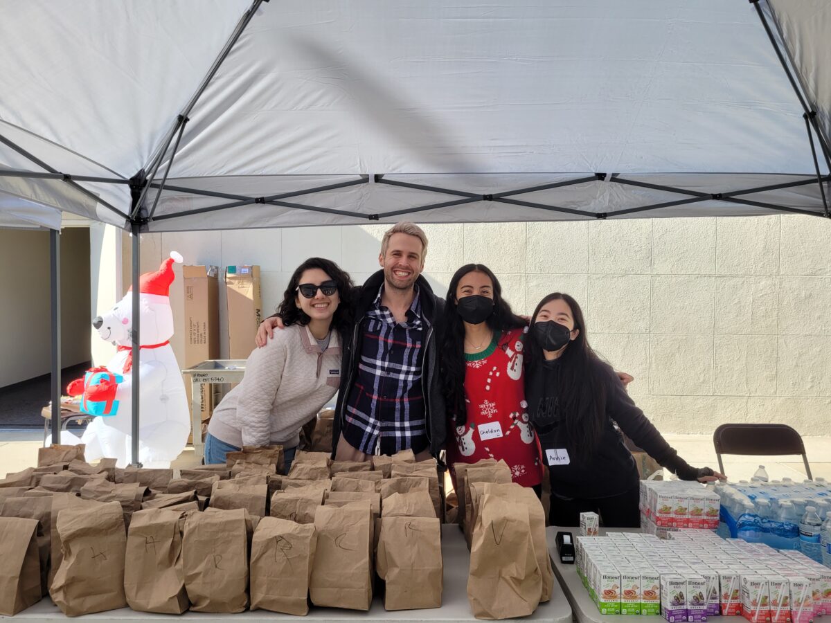 A group of people standing under a tent with bags of food at the live event