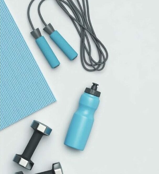 A promotional image for "One Pass Select" featuring text on a white background and fitness equipment, including a blue mat, jump rope, water bottle, and dumbbells on a gray surface.