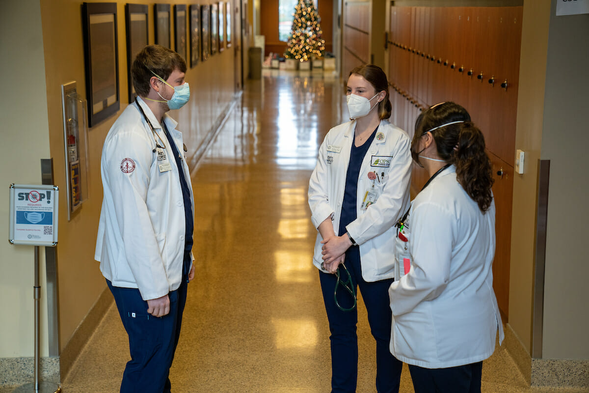 Three students chat in the hallway at WesternU COMP-Northwest in Lebanon, Oregon