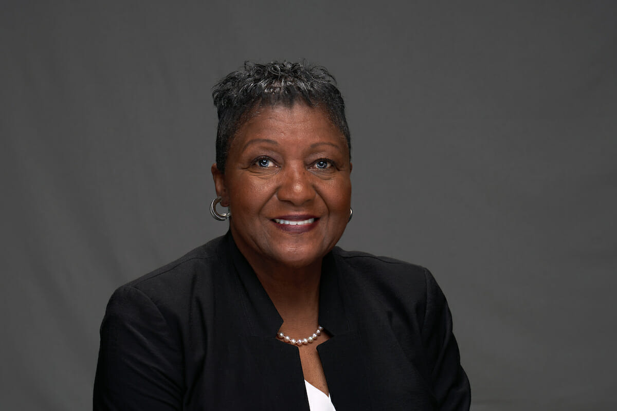 An African-American woman wearing a black jacket and white shirt.