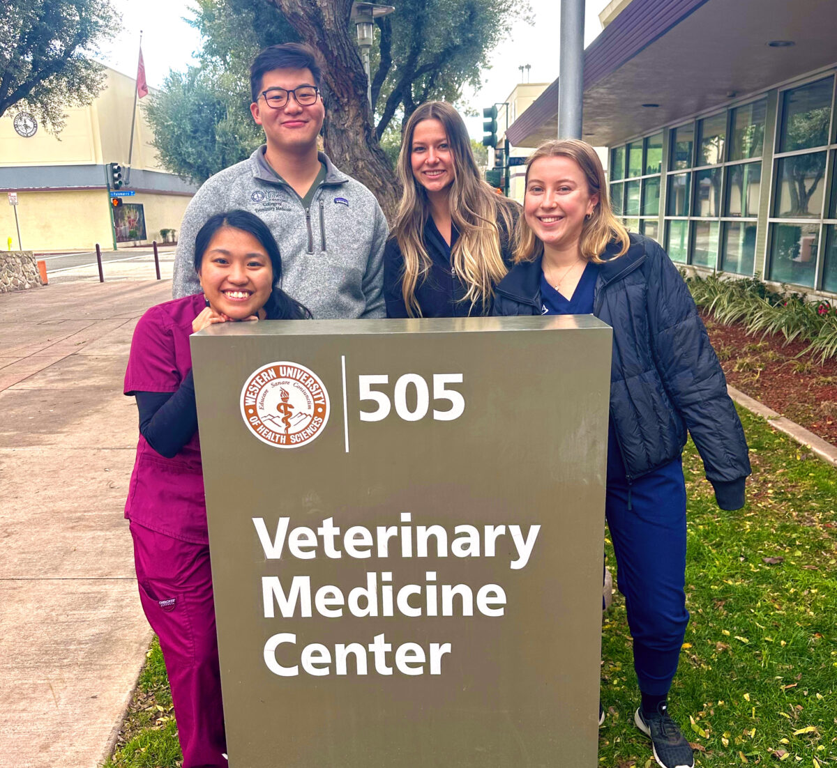 A group of people standing in front of a sign that says veterinary medicine center.