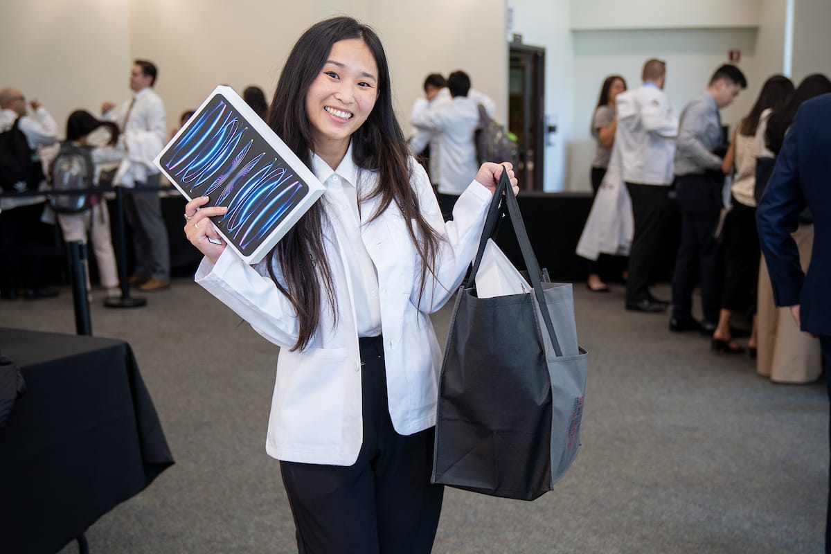 Smiling woman holding bag and folder.