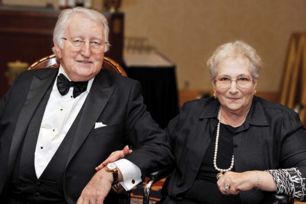 Older man and woman sitting holding hands.