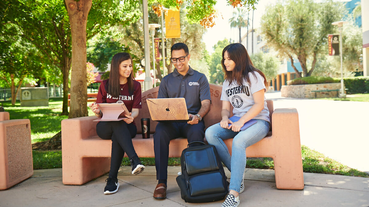 Three students wearing WesternU apparel sitting on bench