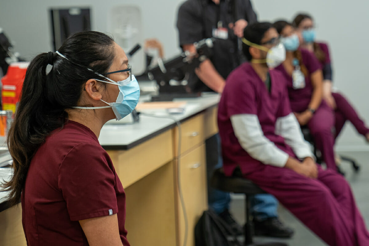 College of Optometry students getting hands-on training in suturing using a suturing pad.