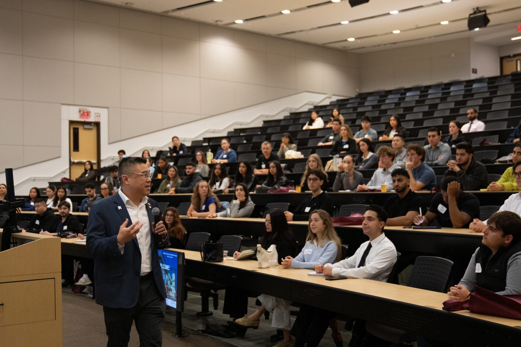 large room, male speaker, people sitting