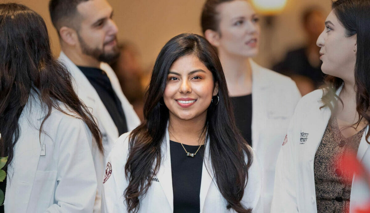 Student with dark hair smiling at the camera