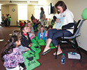 the Gift of Literacy event A picture of children sitting on the floor as they watch a female medical student speak about literacy